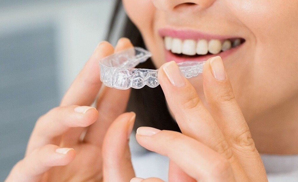 woman holding clear aligner from cosmetic dentist