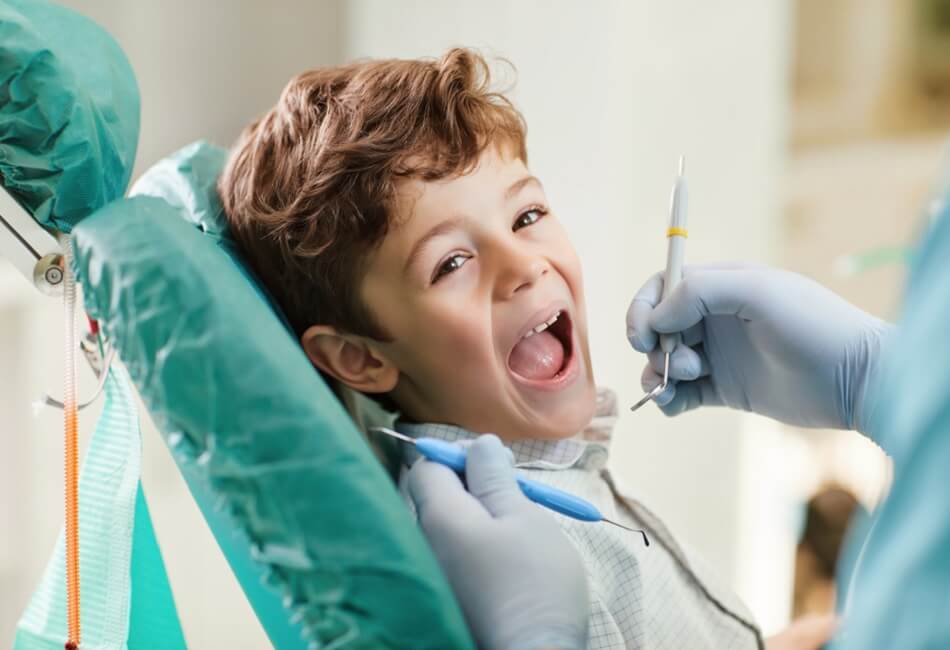 young boy smiling while having dental treatment